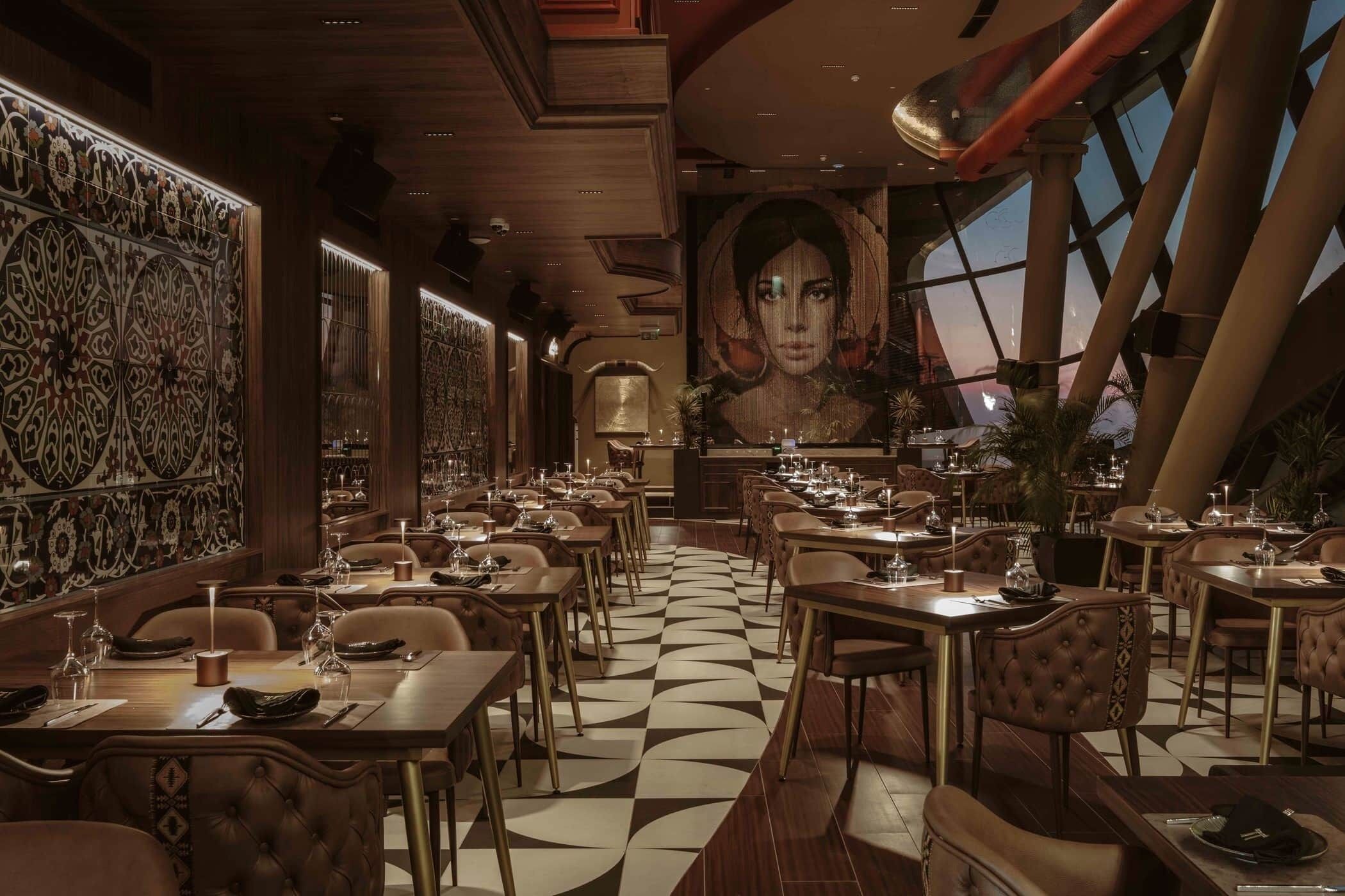 Ein Restaurant mit einem gemusterten Boden, aufwändigen Wandverzierungen und einem großen Wandgemälde.