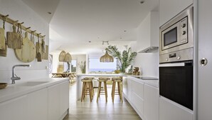 Een moderne keuken met witte kasten, houten stoelen en een groot eiland.