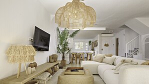 Een moderne woonkamer met een witte bank, een houten salontafel en een grote geweven lamp.