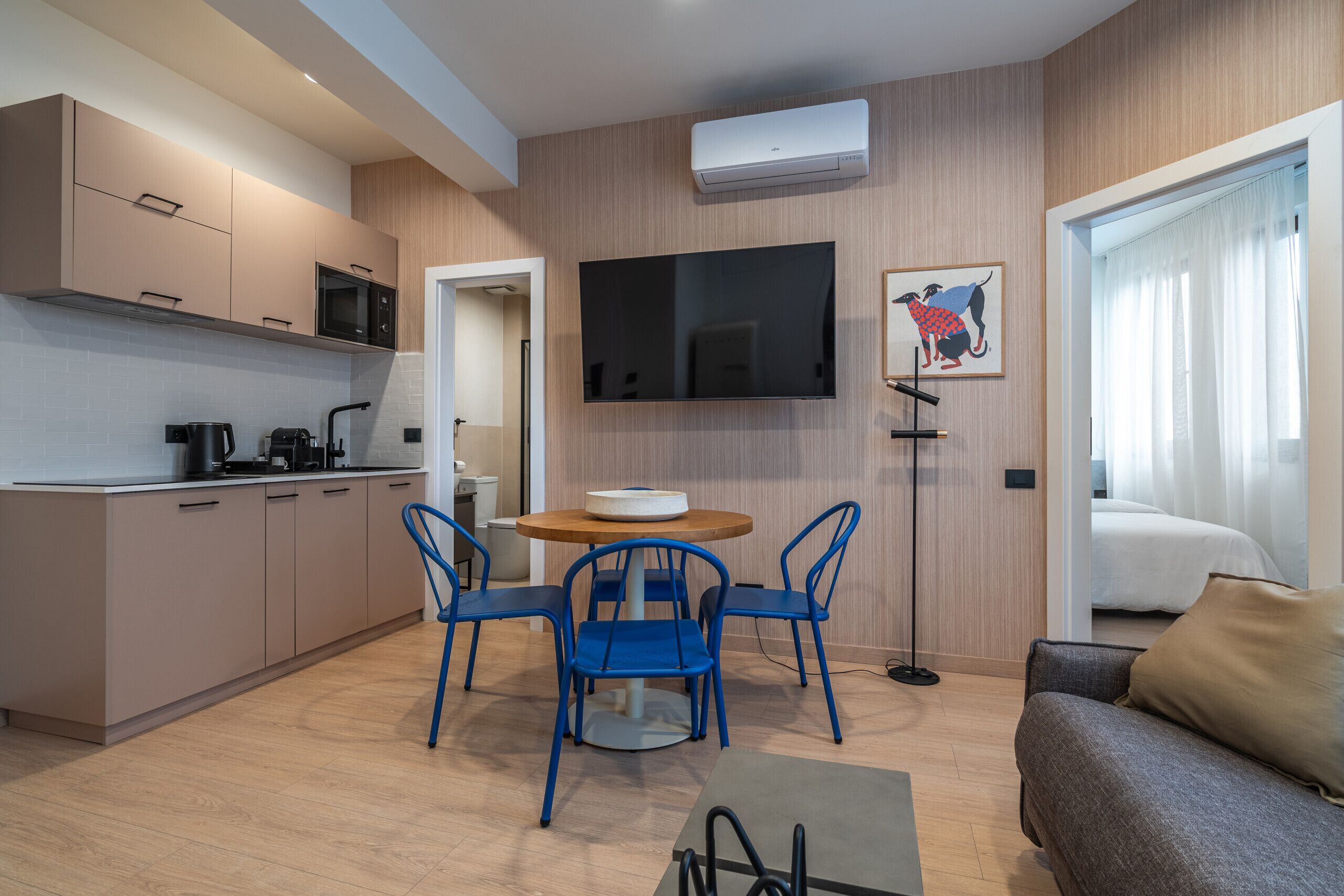 Eine moderne Küche mit Mikrowelle, Herd und Spüle. Ein Essbereich mit Tisch und Stühlen ist vorhanden. Ein Flachbildfernseher ist an der Wand montiert.