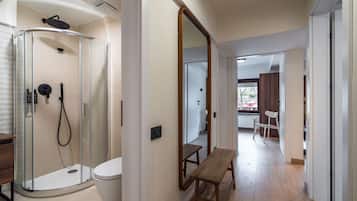 Un baño moderno con ducha de vidrio, inodoro y banco de madera en un pasillo.