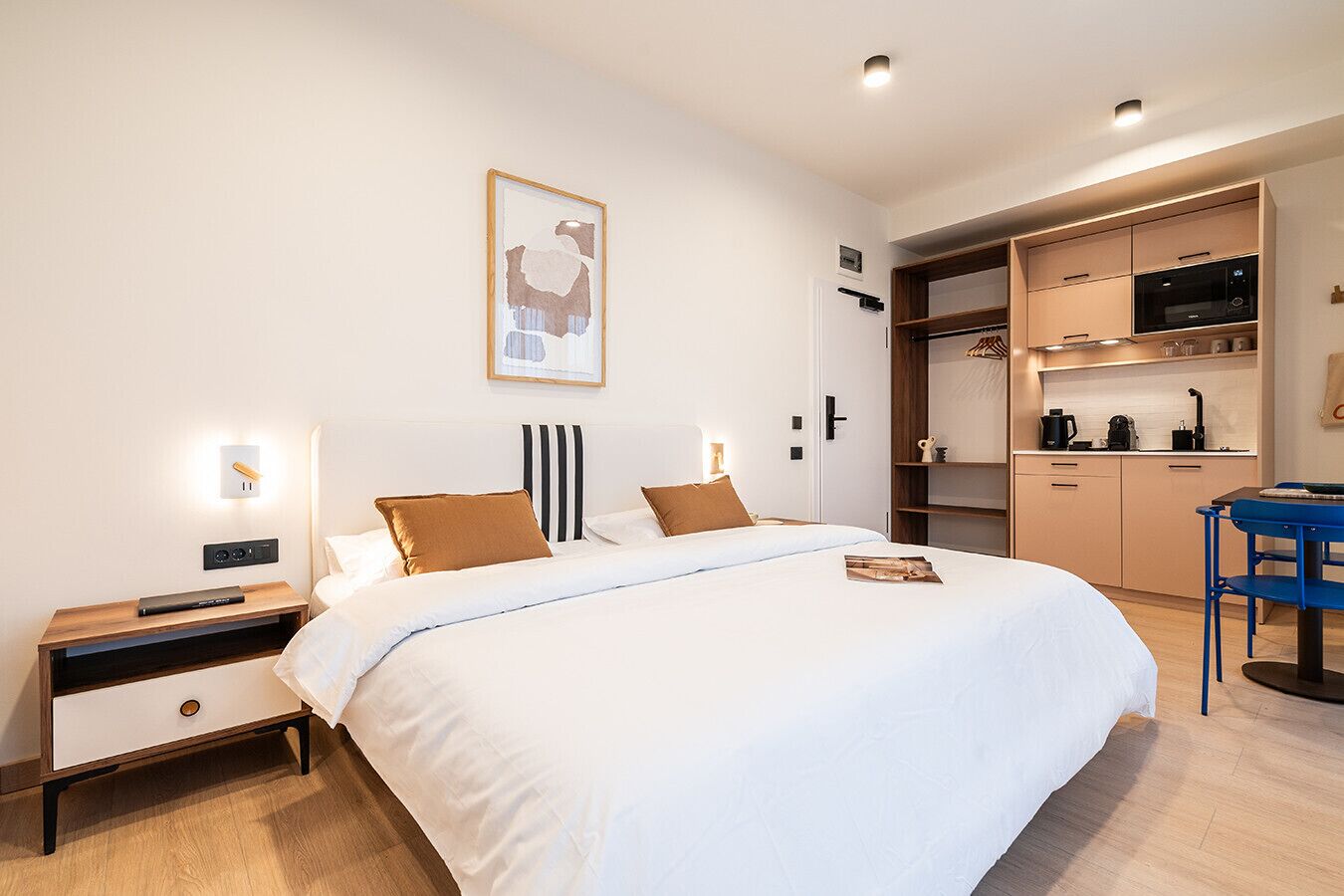 Una habitación de hotel moderna con una cama grande, mesitas de noche, un escritorio y un rincón americano.