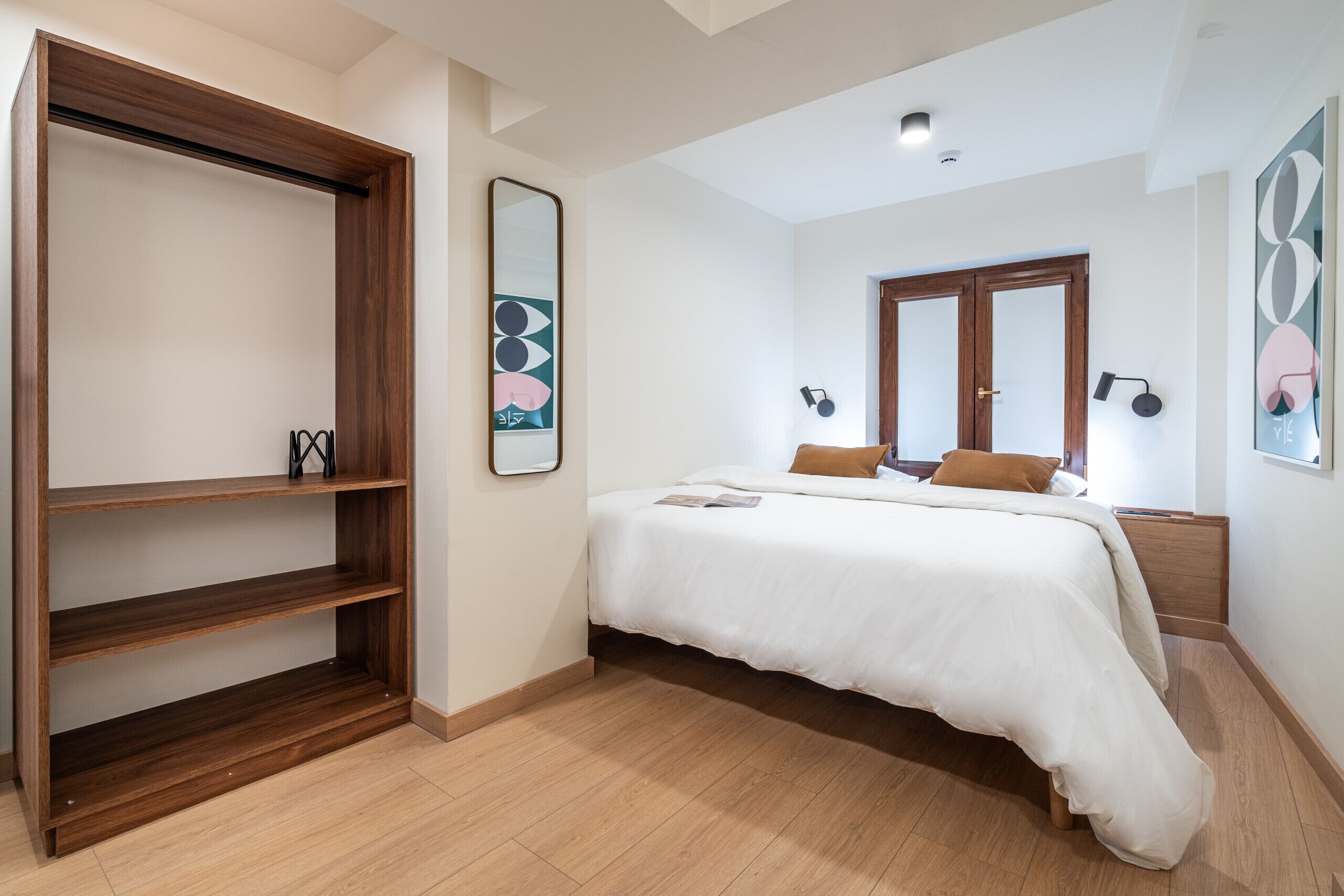 Une chambre à coucher comprenant un lit, une armoire, un miroir et des œuvres d’art murales.