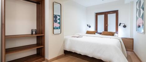 Une chambre à coucher comprenant un lit, une armoire, un miroir et des œuvres d’art murales.