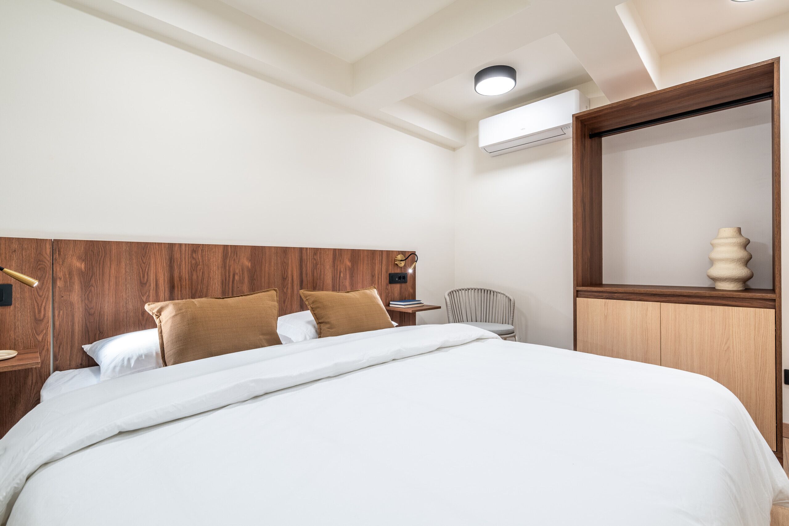 A modern hotel room with a large bed, wooden headboard, and a small table with a chair.