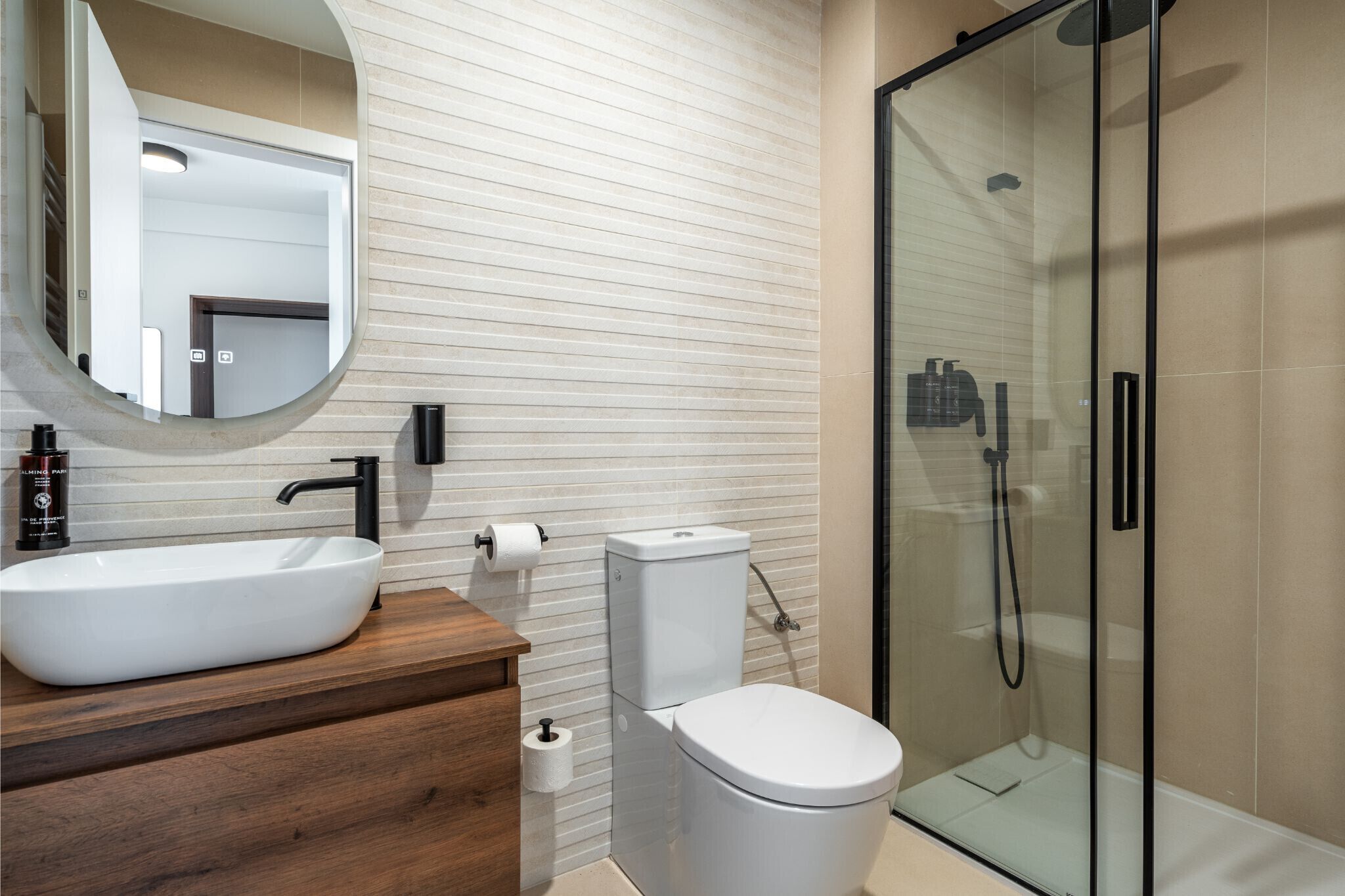 Ein modernes Badezimmer mit einem großen, weißen Waschbecken, einer Toilette und einer Duschkabine.