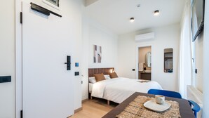 Une chambre d’hôtel avec un lit, une table sur laquelle se trouve une tasse, et vue sur le couloir.