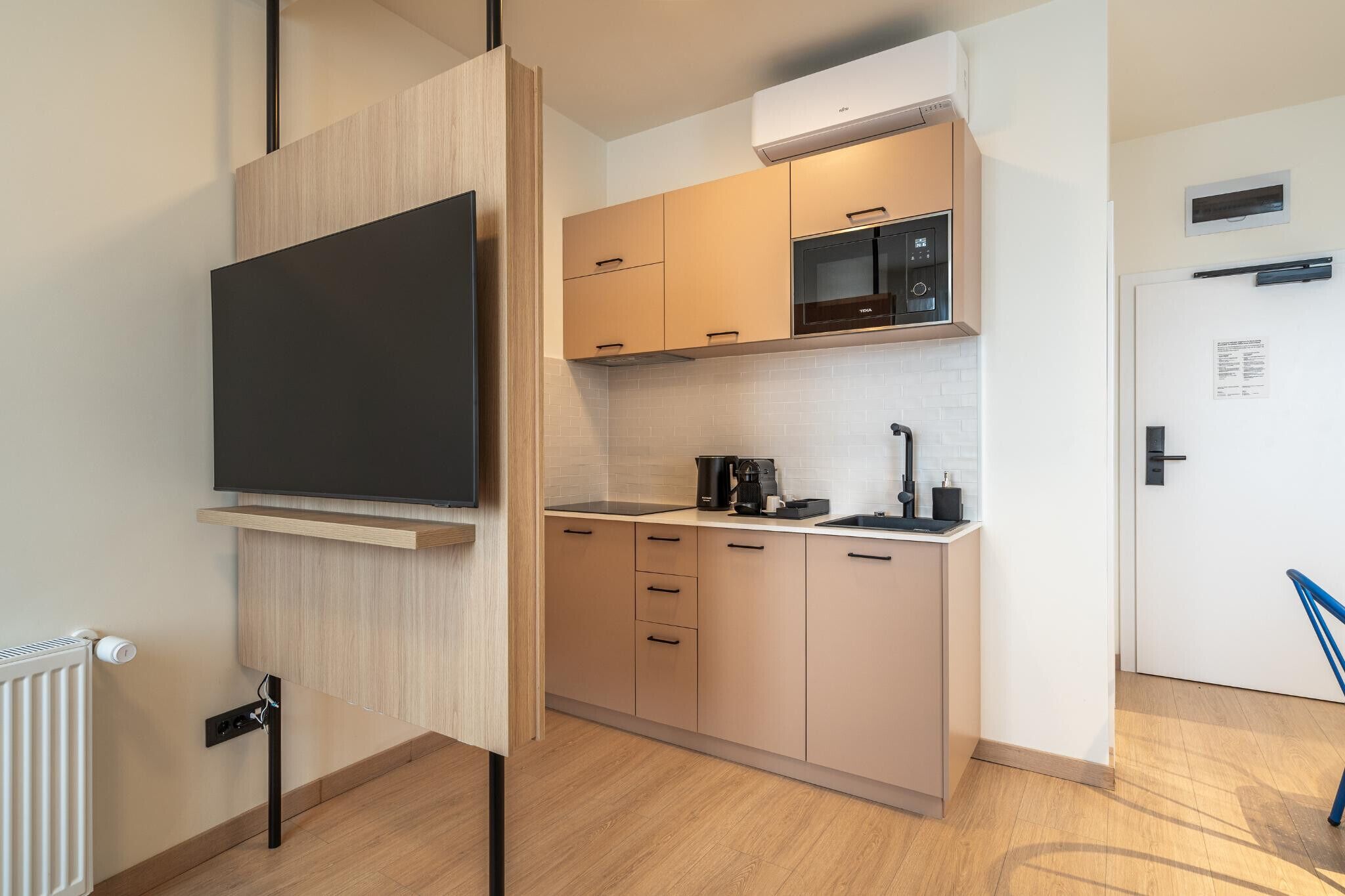 Een moderne keuken met een flatscreen televisie, een magnetron en een koffiezetapparaat.