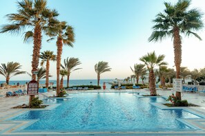 A pool area with lounge chairs and palm trees, overlooking the sea. - Royal Star Beach Resort (Hurghada)