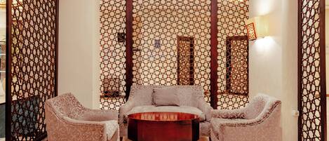 A room with a sofa set, a coffee table, and a decorative screen.
