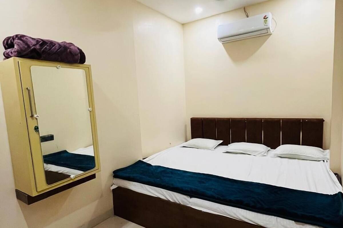 A bedroom with a bed, a wardrobe, a mirror, and an air conditioning unit.