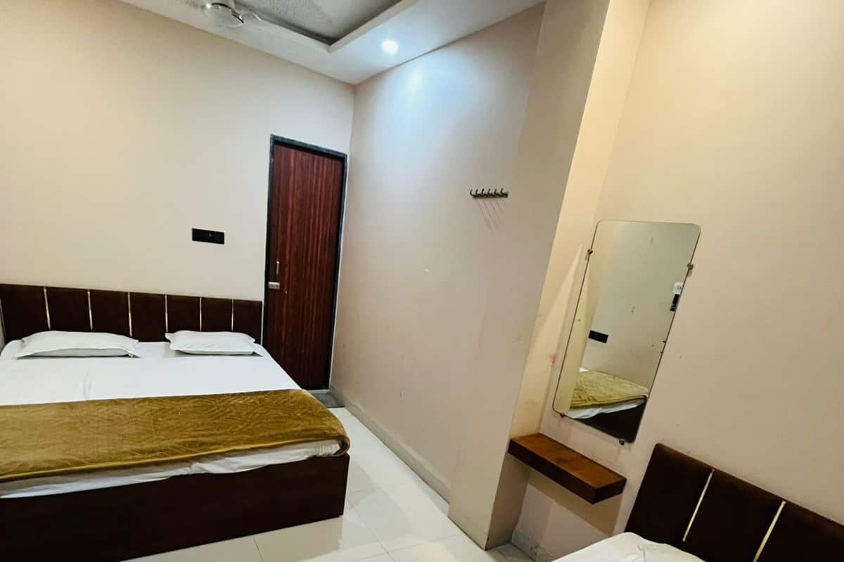 A hotel room with two beds, a mirror, a ceiling fan, and a door.