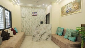 Una zona de recepción con un mostrador de mármol, un sofá con cojines estampados y un televisor montado en la pared.