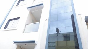 Un edificio moderno con fachada blanca y detalles azules. Cuenta con varios balcones y ventanas amplias.