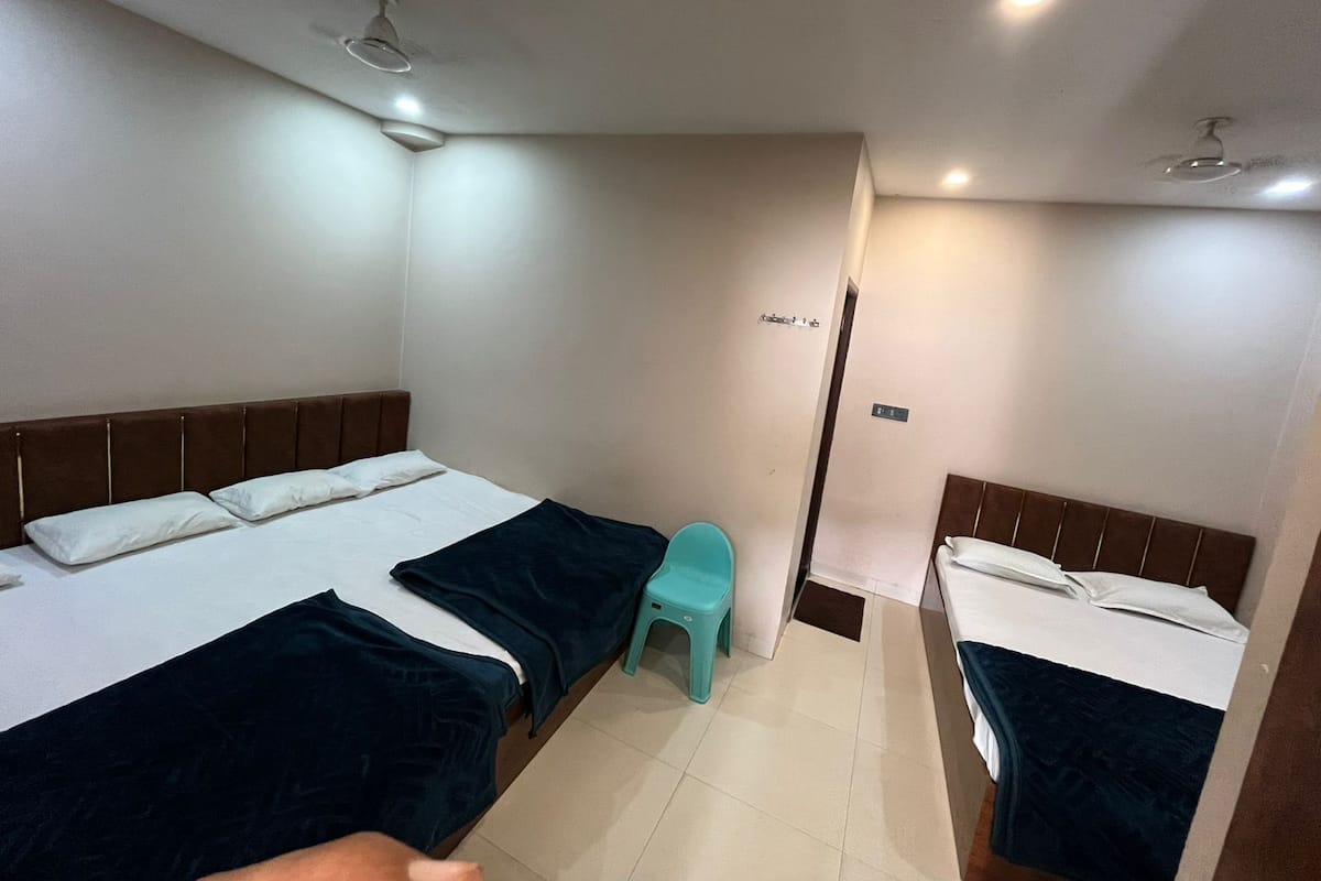 A hotel room with two beds, a small table, and a door leading to another room.