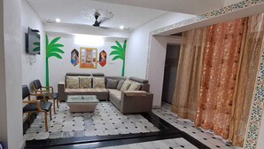 A living room with a sofa, chairs, a coffee table, and decorative wall art. -  Connecting you with the Heritage & History of Udaipur. (Udaipur)