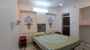 A bedroom with a bed, two nightstands, a window, and decorative wall art. -  Connecting you with the Heritage & History of Udaipur. (Udaipur)