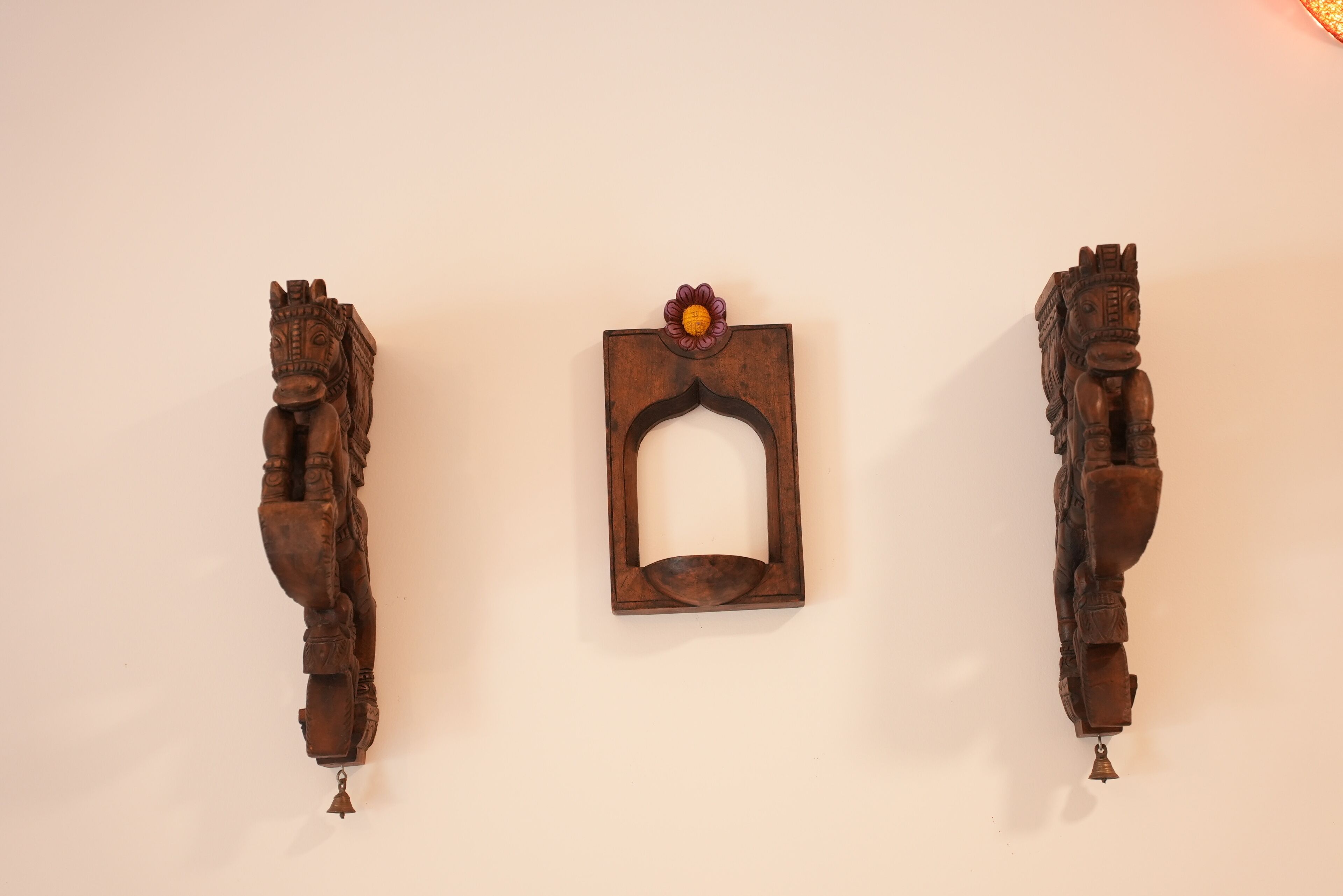 Three wooden horse sculptures mounted on a wall.