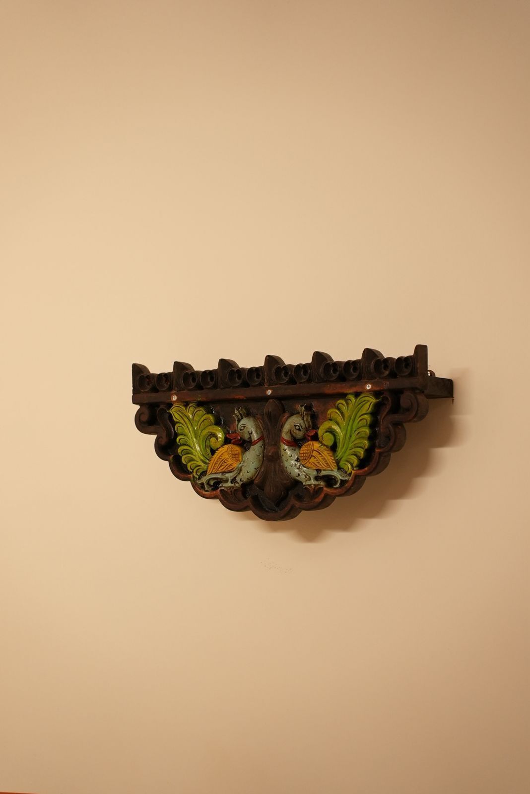 A wall-mounted decorative piece with a carved design and two bird figures.