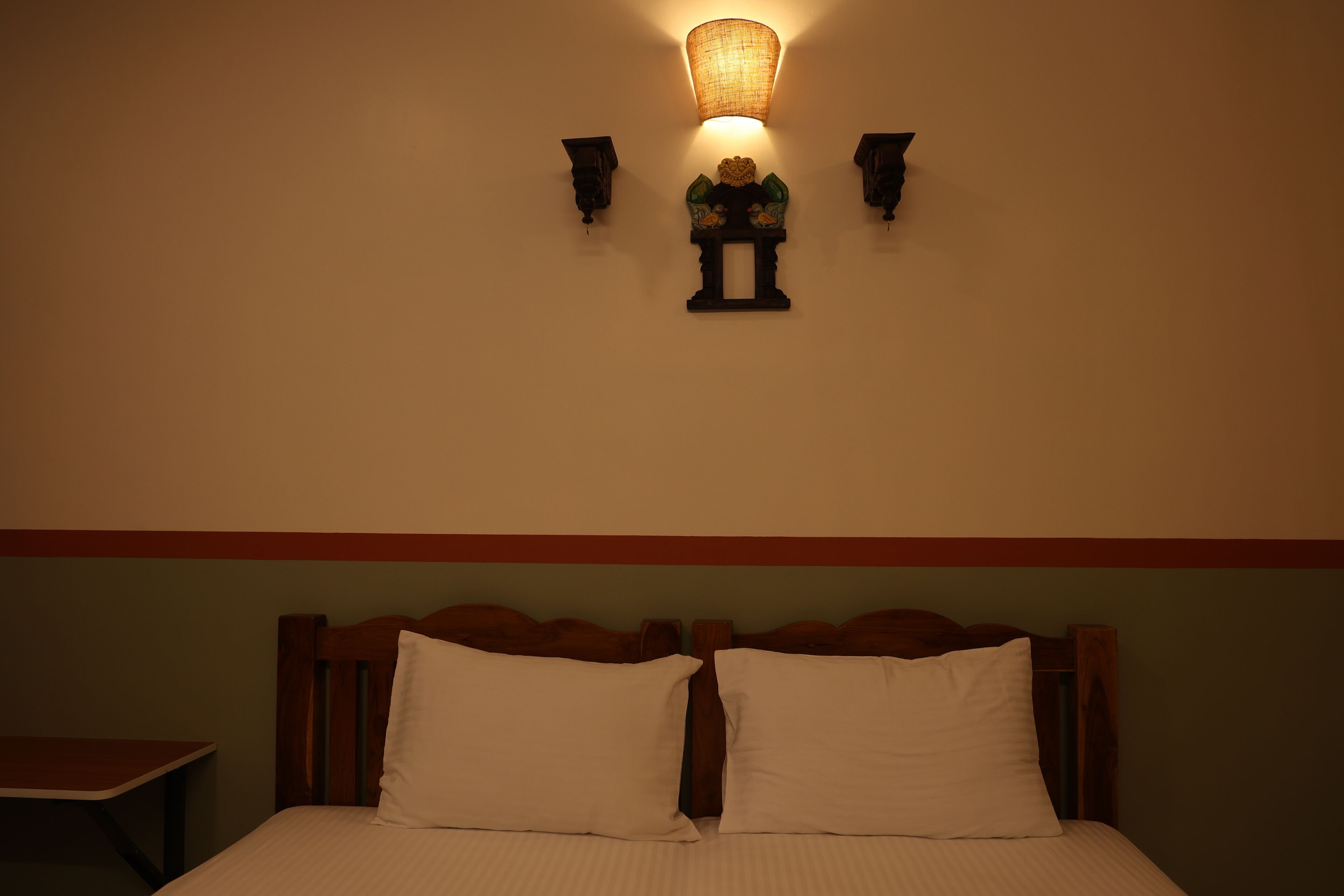 A bedroom with a bed, a nightstand, and a wall-mounted lamp.