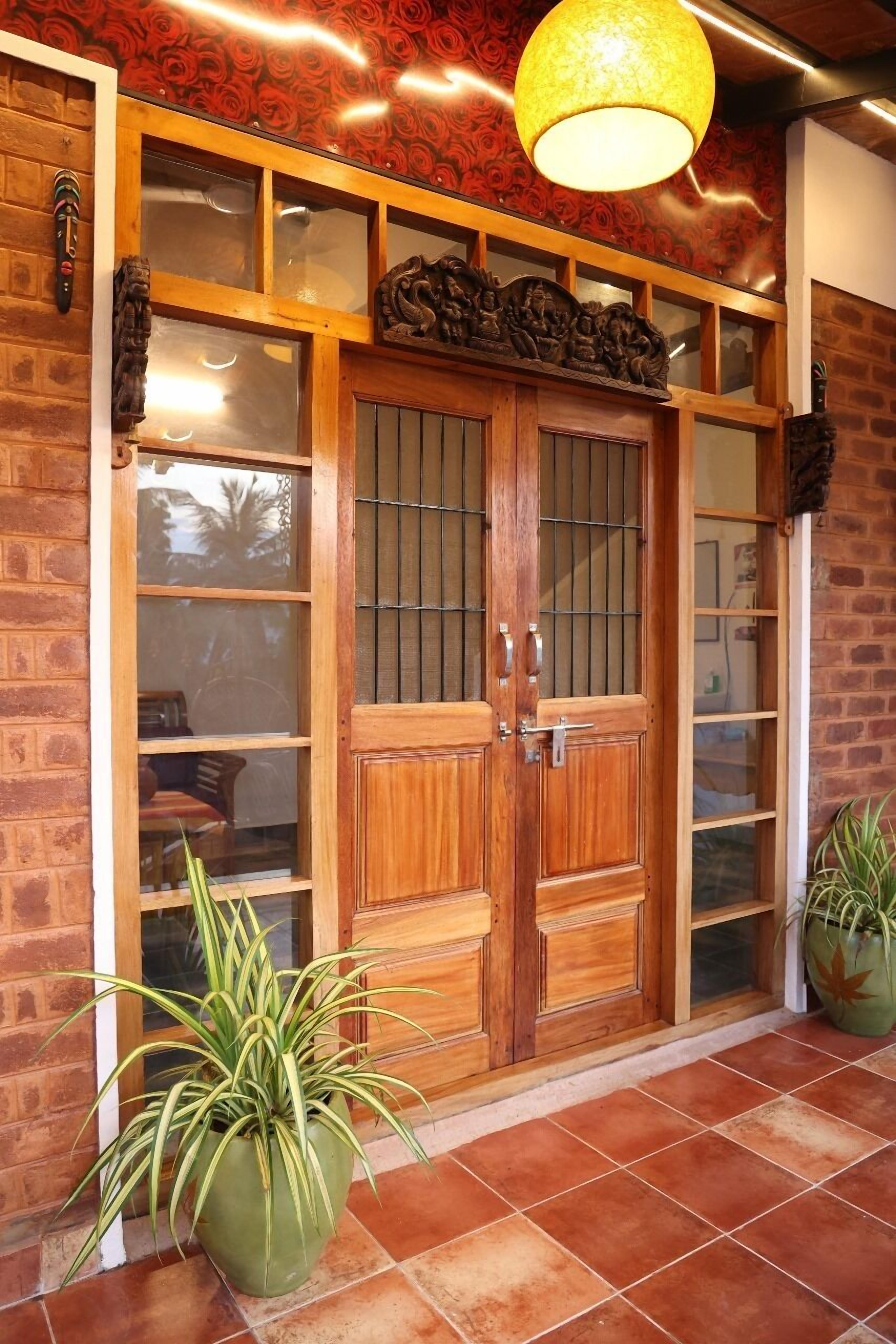 A wooden door with glass panels, a hanging light fixture, and potted plants.