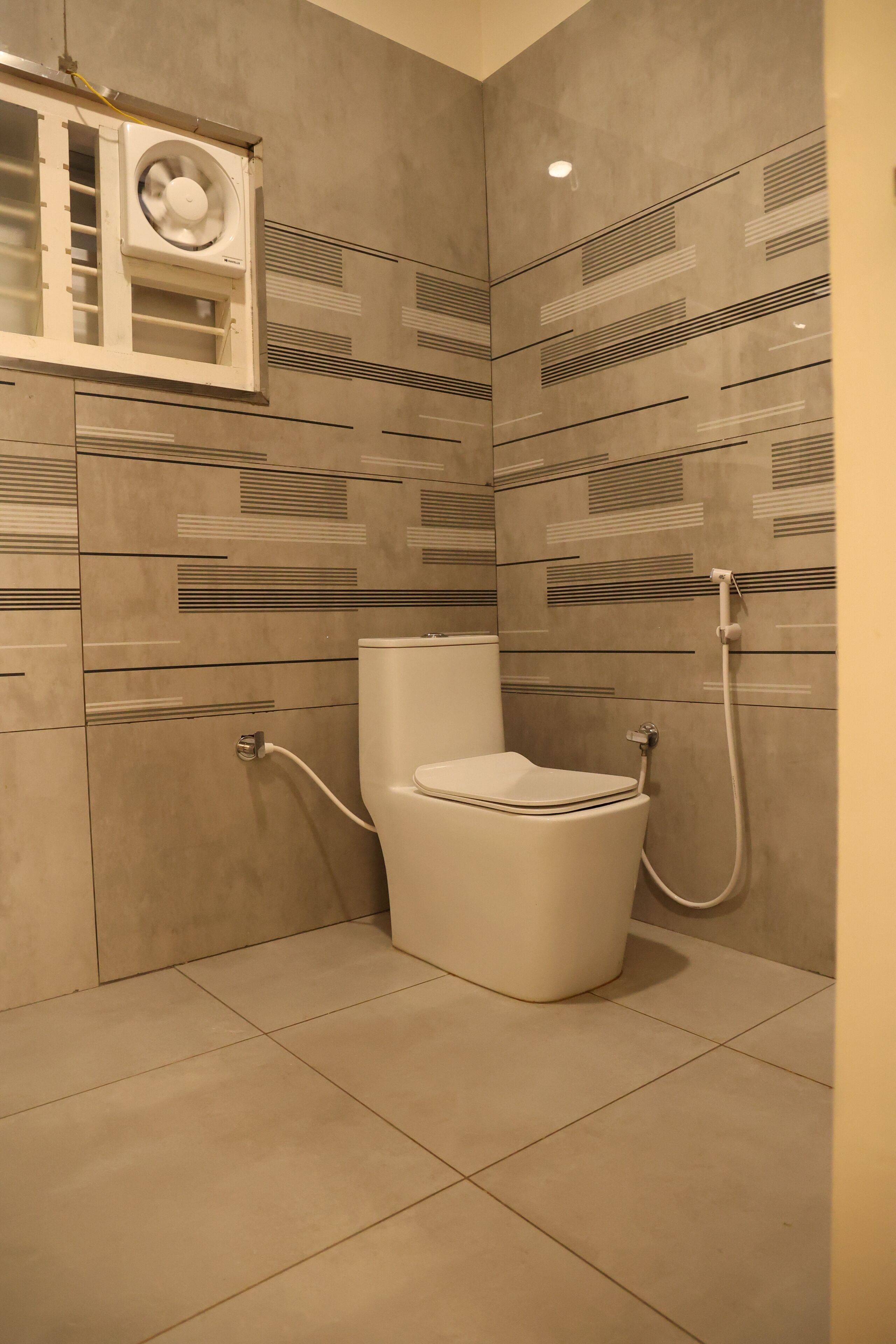 Un baño moderno con inodoro, ducha y extractor de aire.