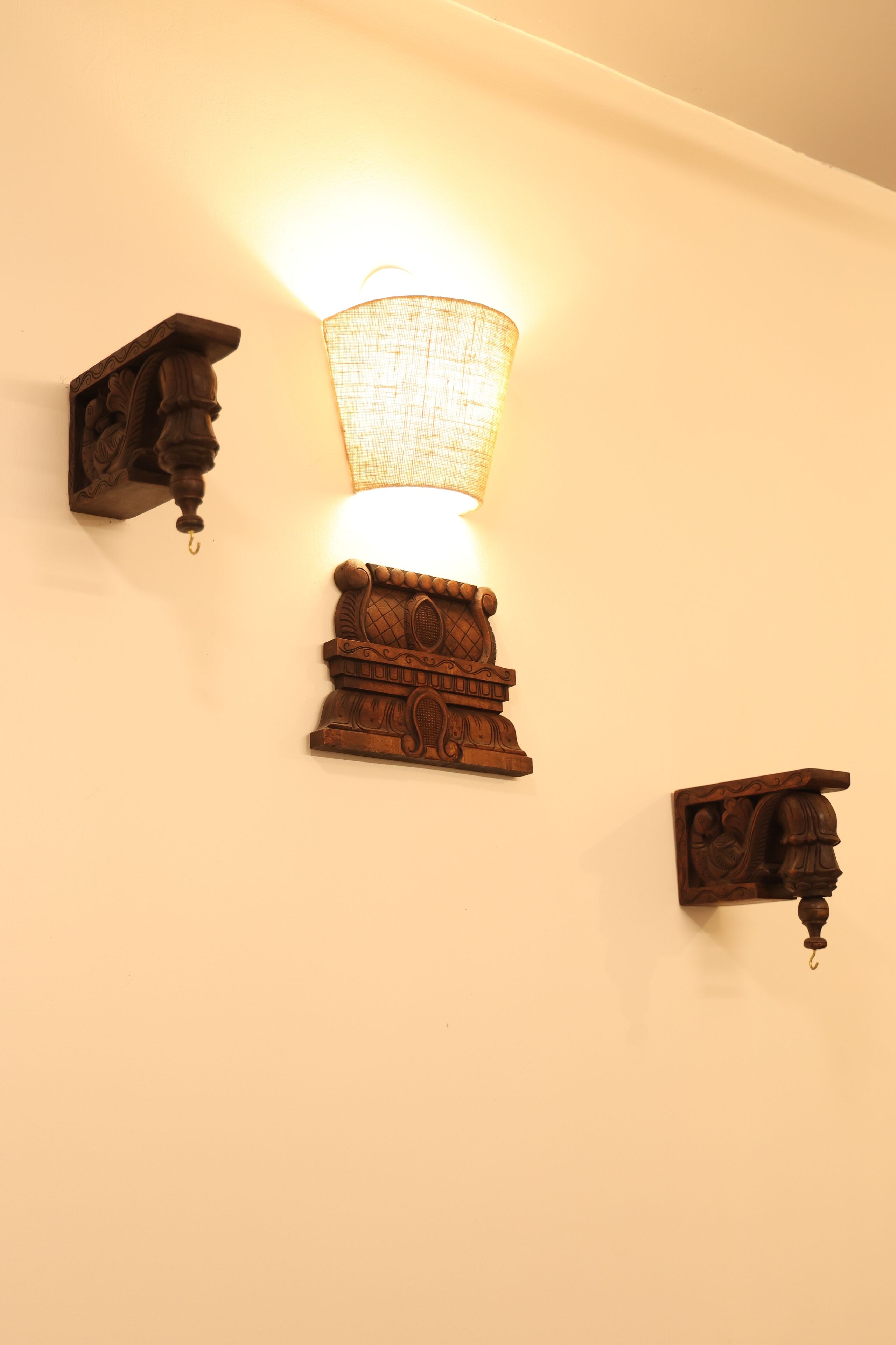 A wall-mounted light fixture with a decorative base and a hanging shade.