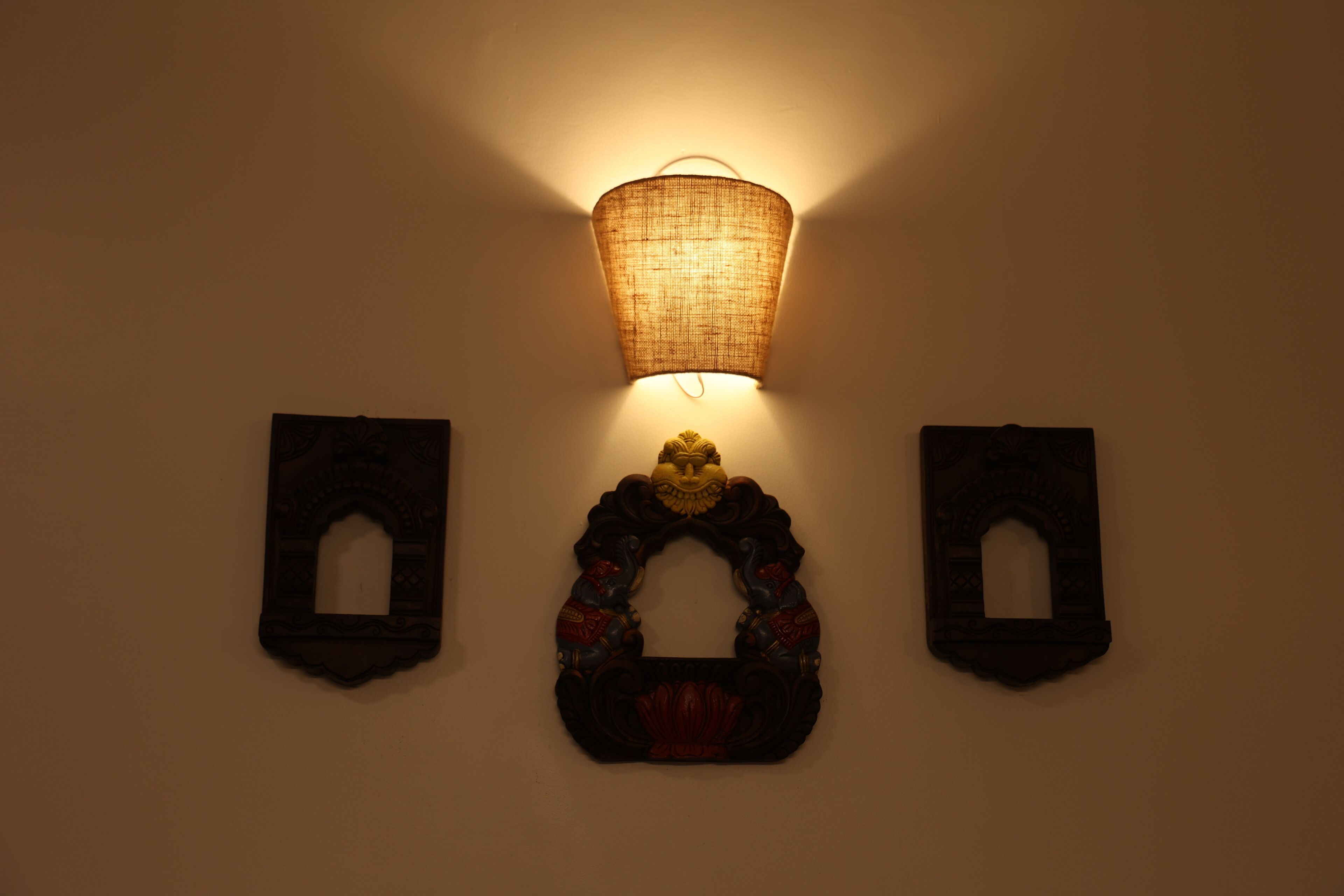 En väggmonterad lampa med en flätad lampskärm och två dekorativa paneler på vardera sidan.