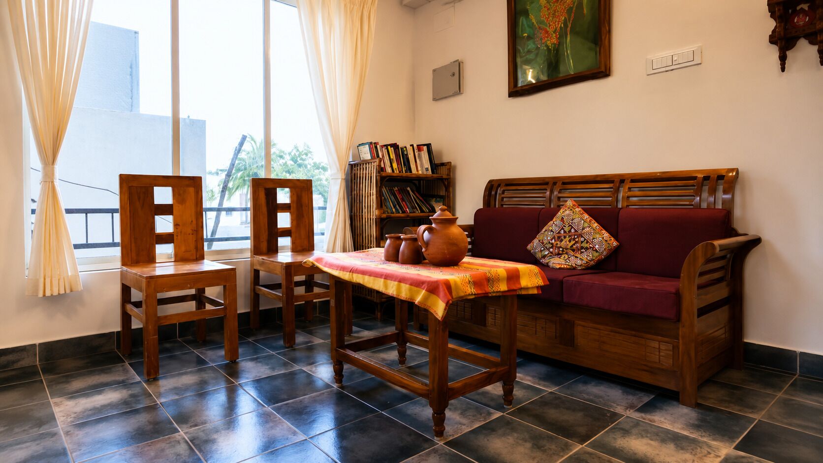 A room with a wooden sofa, a wooden table with a cloth, a chair, a bookshelf, and a window with curtains.