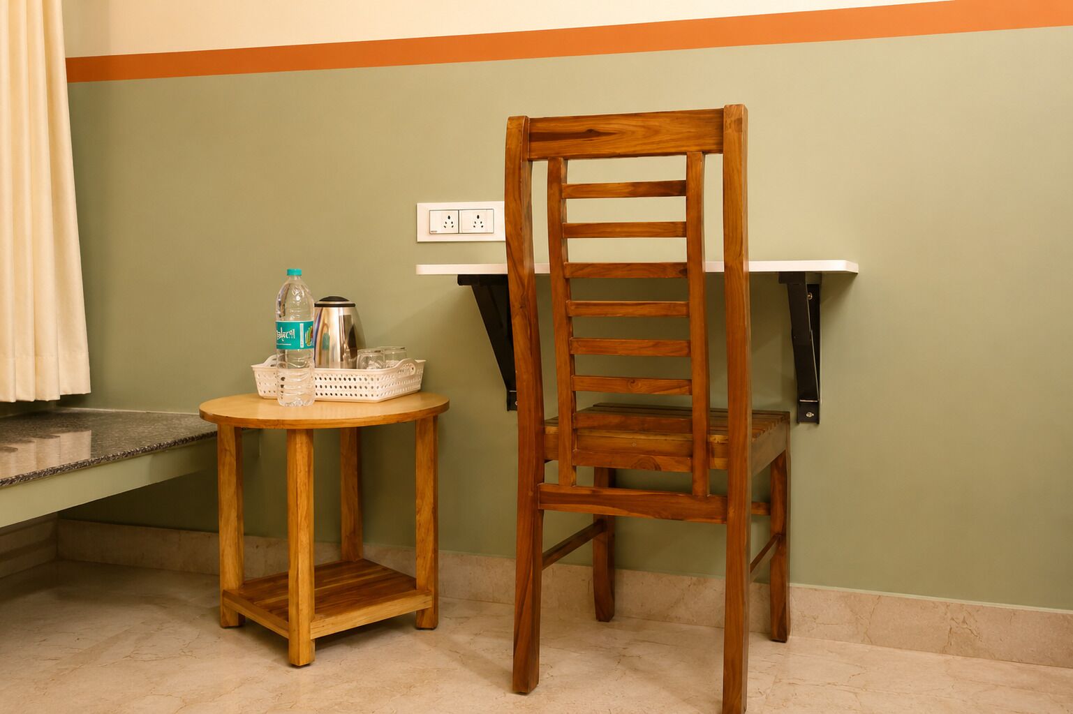 A wooden chair and a small round table with a water bottle and a kettle.