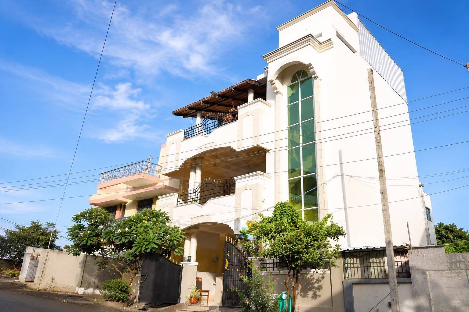A two-story building with a balcony on the upper floor, a large window on the right, and a gate at the entrance.