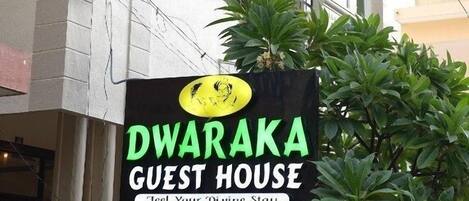 A sign for 'DWARAKA GUEST HOUSE' with contact numbers.