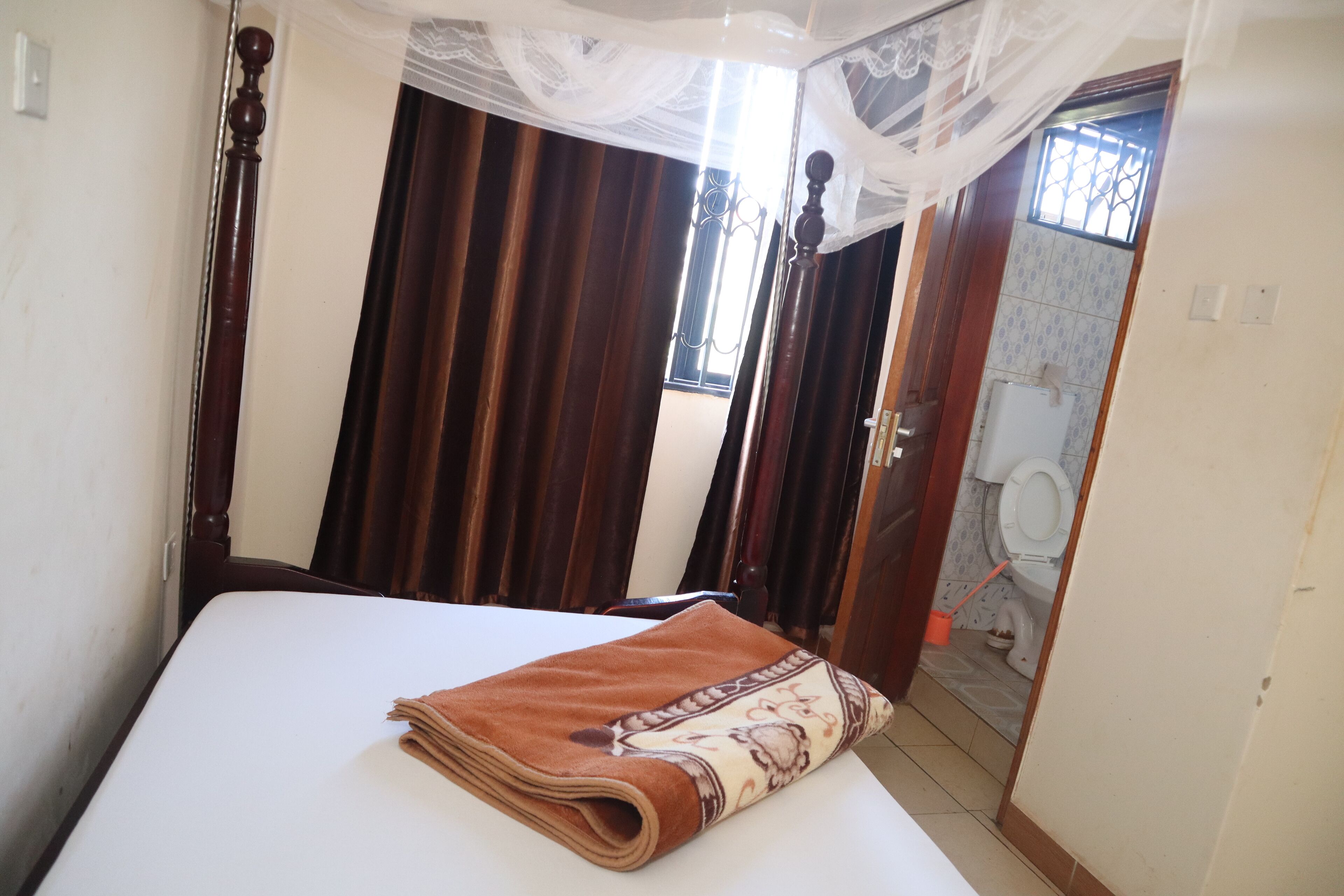 A hotel room with a bed, curtains, a window, and a bathroom visible through an open door.