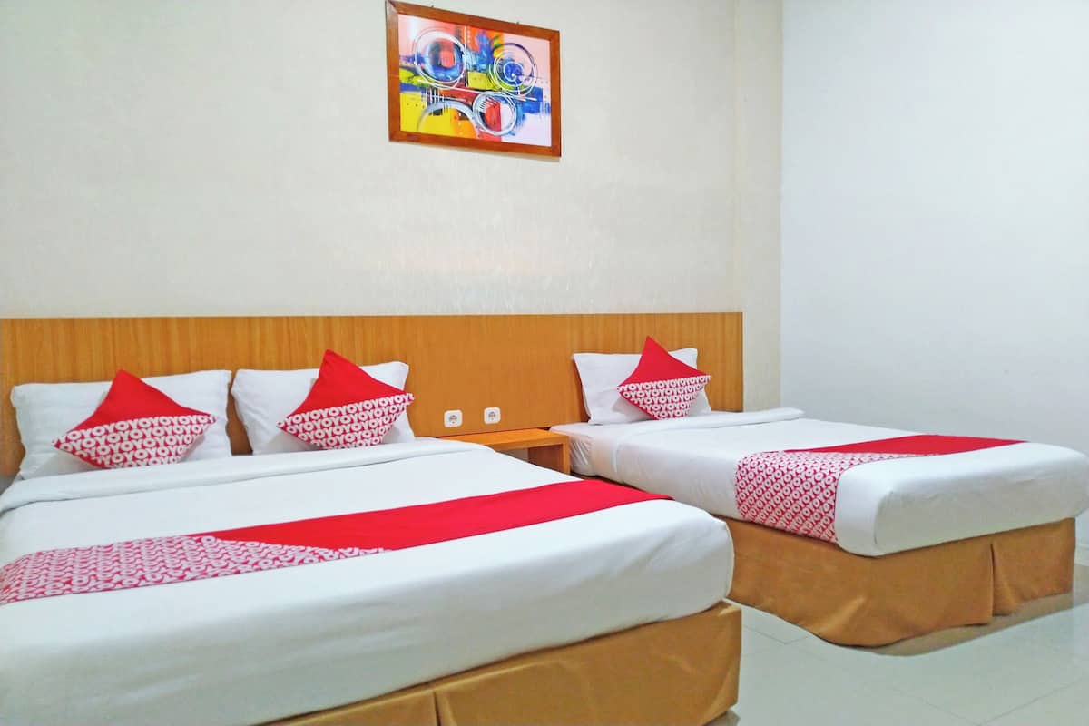 Een hotelkamer met twee bedden, elk voorzien van wit beddengoed en rode accenten, een houten hoofdbord en een kleurrijk abstract schilderij aan de muur.