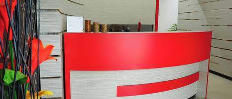 Un mostrador de recepción de diseño curvo, con una decoración en blanco y rojo y jarrones decorativos encima.