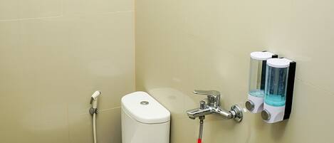 Baño con inodoro, bidé, lavamanos y cabezal de ducha.