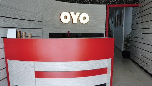 A reception desk with a red and white color scheme, a sign reading "OYO", and a modern interior design with patterned walls and a tiled floor. - Hotel O Bukittinggi near Jam Gadang formerly Hotel Aedo (Bukittinggi)