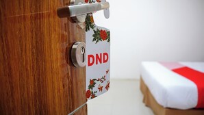 A wooden door with a key lock and a metal handle. A sign with the letters "DND" is attached to the door. - Hotel O Bukittinggi near Jam Gadang formerly Hotel Aedo (Bukittinggi)