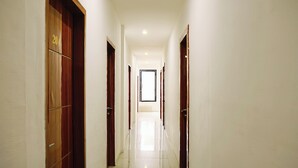 A long, narrow hallway with wooden doors on both sides, leading to a bright room at the end. - Hotel O Bukittinggi near Jam Gadang formerly Hotel Aedo (Bukittinggi)
