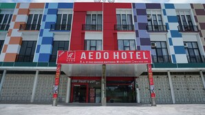 A hotel with a colorful facade, a prominent red sign for the Aedohotel, and multiple balconies. - Hotel O Bukittinggi near Jam Gadang formerly Hotel Aedo (Bukittinggi)