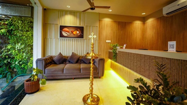 A reception area with a sofa, a decorative lamp, and a wall-mounted air conditioning unit. - Saba's Courtyard (Colachel)