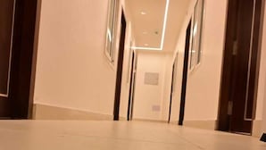 A long, narrow hallway with a polished floor, recessed lighting, and doors on both sides. - Saba's Courtyard (Colachel)