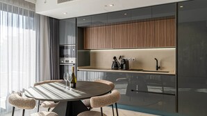 A modern kitchen with a round dining table, cushioned chairs, and built-in appliances. - Mercury Suite Designer Apartment with Pool Access (San Ġiljan)