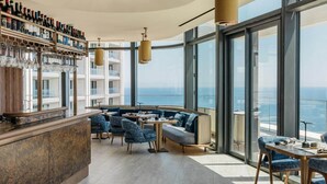 A high-rise bar with a panoramic ocean view, modern seating, and a wine rack. - Mercury Suite Designer Apartment with Pool Access (San Ġiljan)