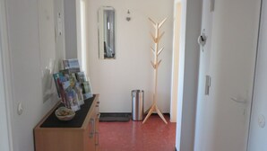A hallway with a reception desk, a coat rack, a trash bin, and a door. - Apartment 'City View' with Private Terrace and Wi-Fi (Bräunlingen)