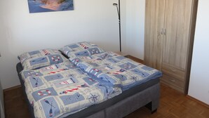 A bedroom with a bed, a wardrobe, a floor lamp, and a painting on the wall. - Apartment 'City View' with Private Terrace and Wi-Fi (Bräunlingen)