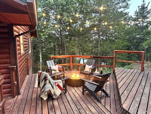 A wooden deck with a fire pit, outdoor seating, and string lights. - Peaceful Lakefront 2 Bedroom Cabin Overlooking Table Lake (Golden)