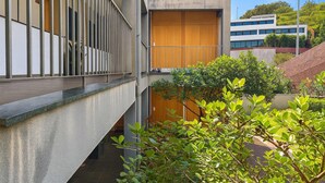 Un edificio moderno con facciata in cemento, una porta in legno e una ringhiera in metallo.