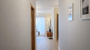 Un corridoio con una porta in legno, una lampada da terra e un quadro appeso al muro.