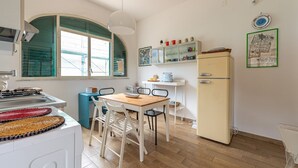 A compact kitchen with a dining table, chairs, a refrigerator, and a window with a view. - Casa Bouganvillea con Terrazza by Wonderful Italy (Isola delle Femmine)
